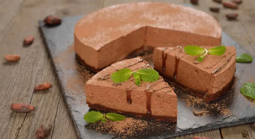 Deliziosa bavarese al cioccolato, cosparsa di cacao e decorata con menta fresca. Due fette sono già state servite.
