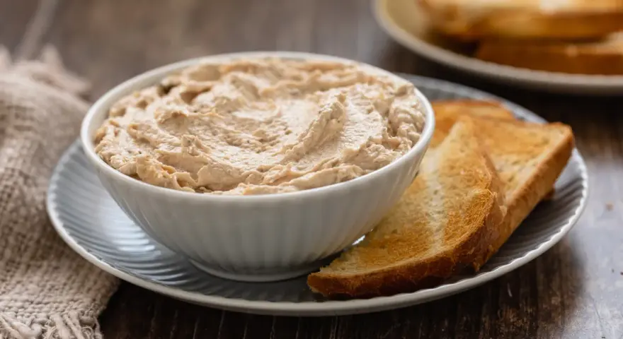 Una ciotola di cremosa mousse di tonno, servita con fette di pane tostato dorato. Perfetta per un aperitivo veloce.