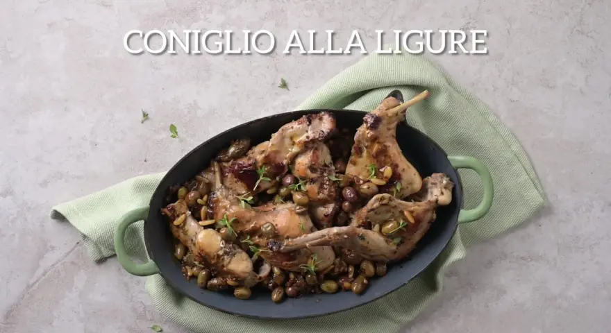 Un saporito coniglio alla ligure, cotto con olive e pinoli, servito in una casseruola verde.
