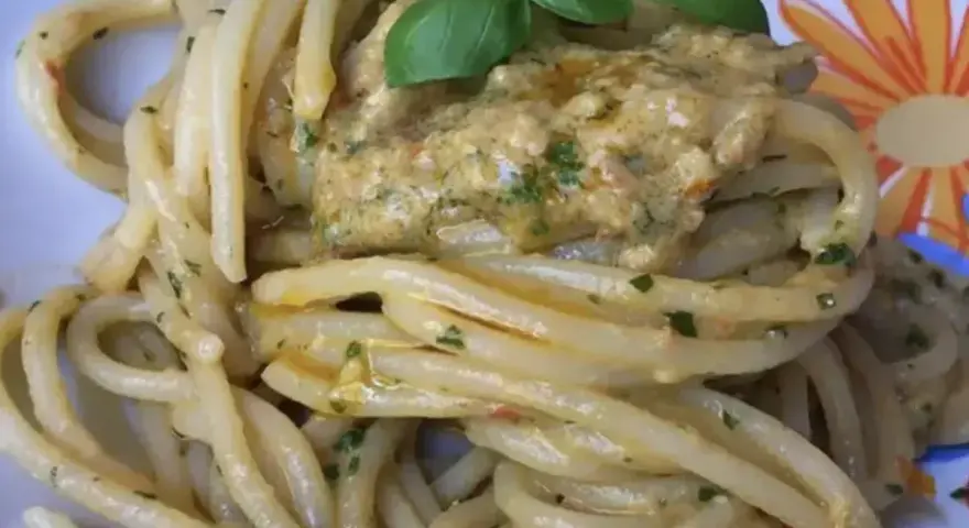 Un piatto invitante di pasta alla carlofortina, condita con un sugo cremoso e guarnita con basilico fresco.