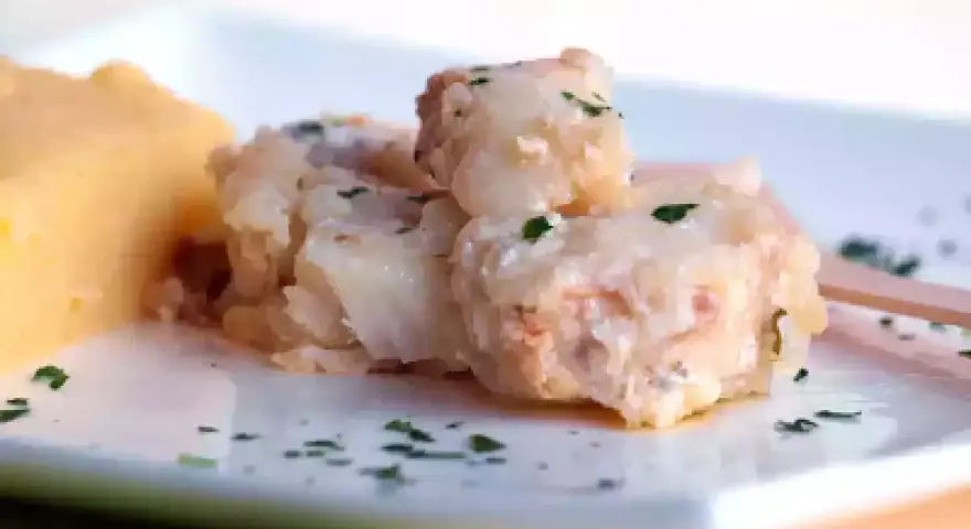Piatto di baccalà alla vicentina cremoso e saporito, servito con una porzione di polenta morbida.
