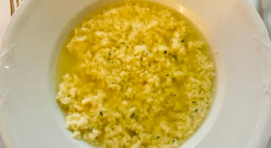 Stracciatella alla romana in una ciotola bianca, un piatto caldo e confortante con uova, parmigiano e prezzemolo.