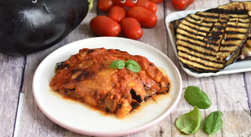 Parmigiana di melanzane grigliate, un piatto saporito con melanzane grigliate, pomodoro e basilico fresco.