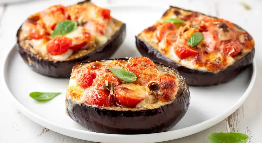 Melanzane ripiene al forno velocissime, con pomodorini, formaggio filante e basilico fresco. Un piatto invitante e facile da preparare.
