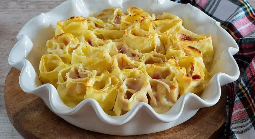 Deliziosi nidi di rondine ripieni di prosciutto e formaggio, cotti al forno in una teglia bianca.