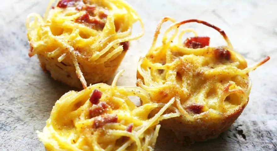 Tre deliziose frittate di pasta, dorate e con pezzetti di pancetta, pronte per essere gustate.