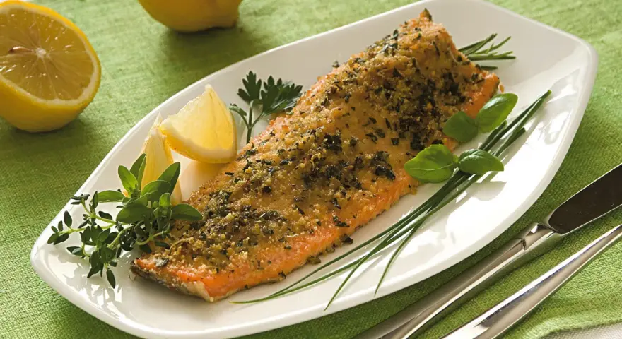 Deliziosa trota salmonata al forno, croccante e profumata, servita con limone fresco e erbe aromatiche.