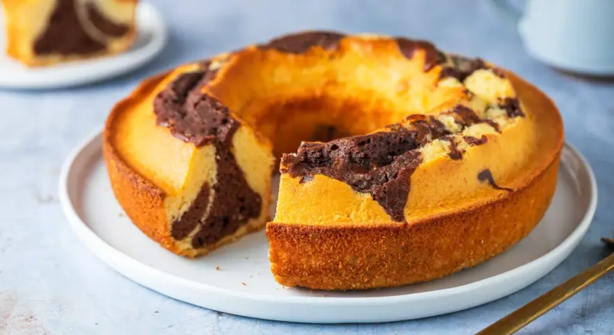 Un ciambellone soffice bicolore, con un invitante contrasto tra pasta chiara e cacao, pronto per essere gustato.
