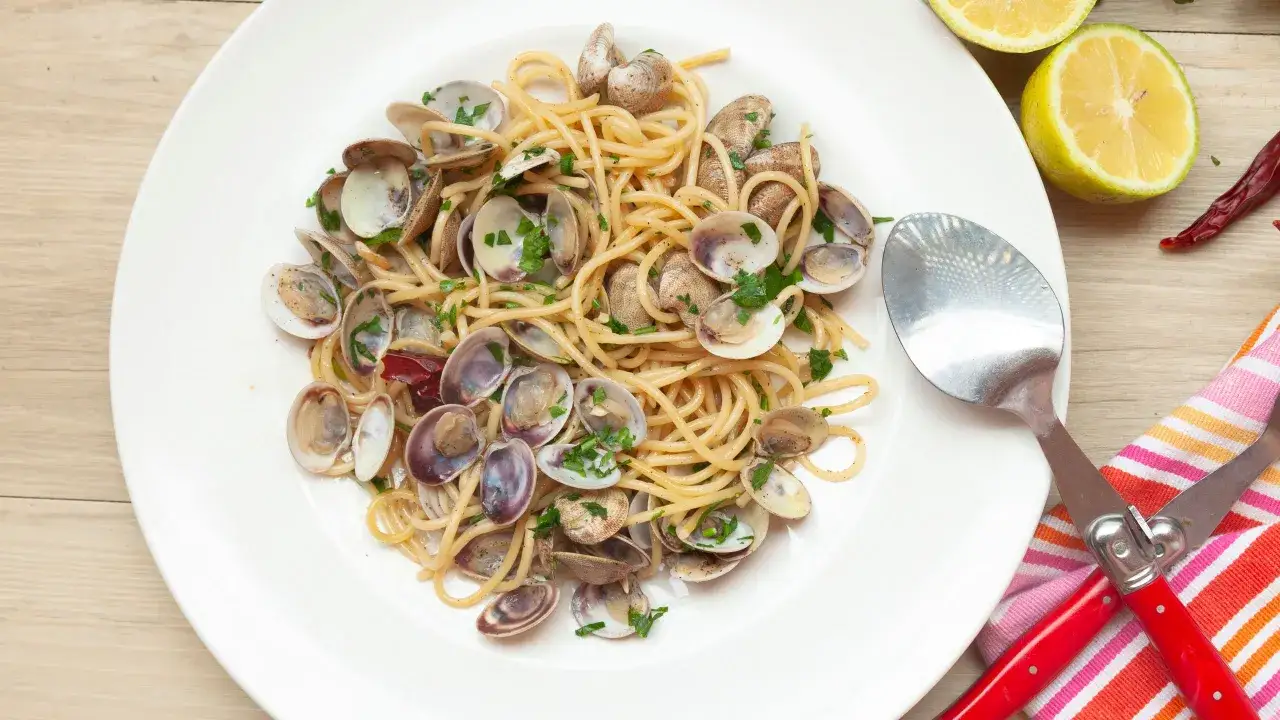 Spaghetti alle vongole surgelate, un piatto gustoso con vongole, prezzemolo e limone.