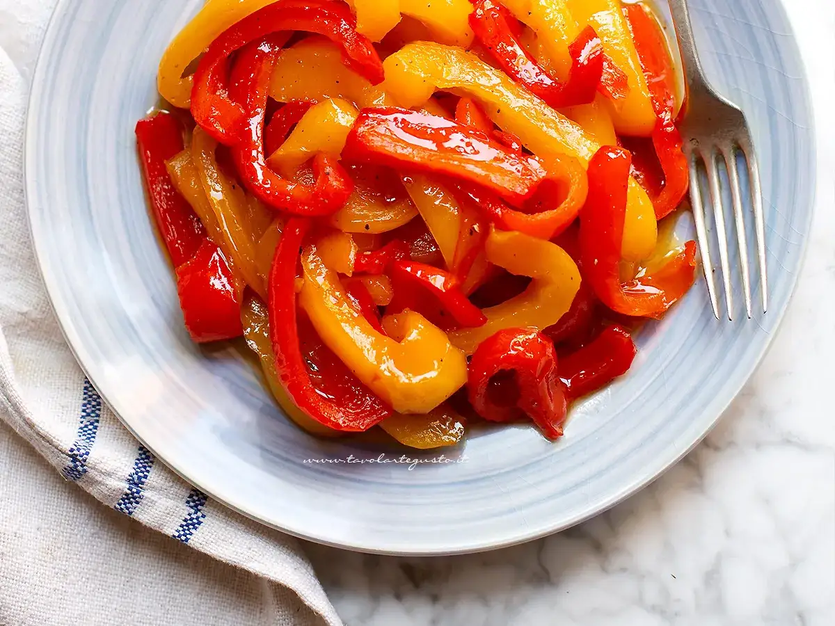 Peperoni in agrodolce, un contorno colorato e saporito, serviti su un piatto azzurro con forchetta.