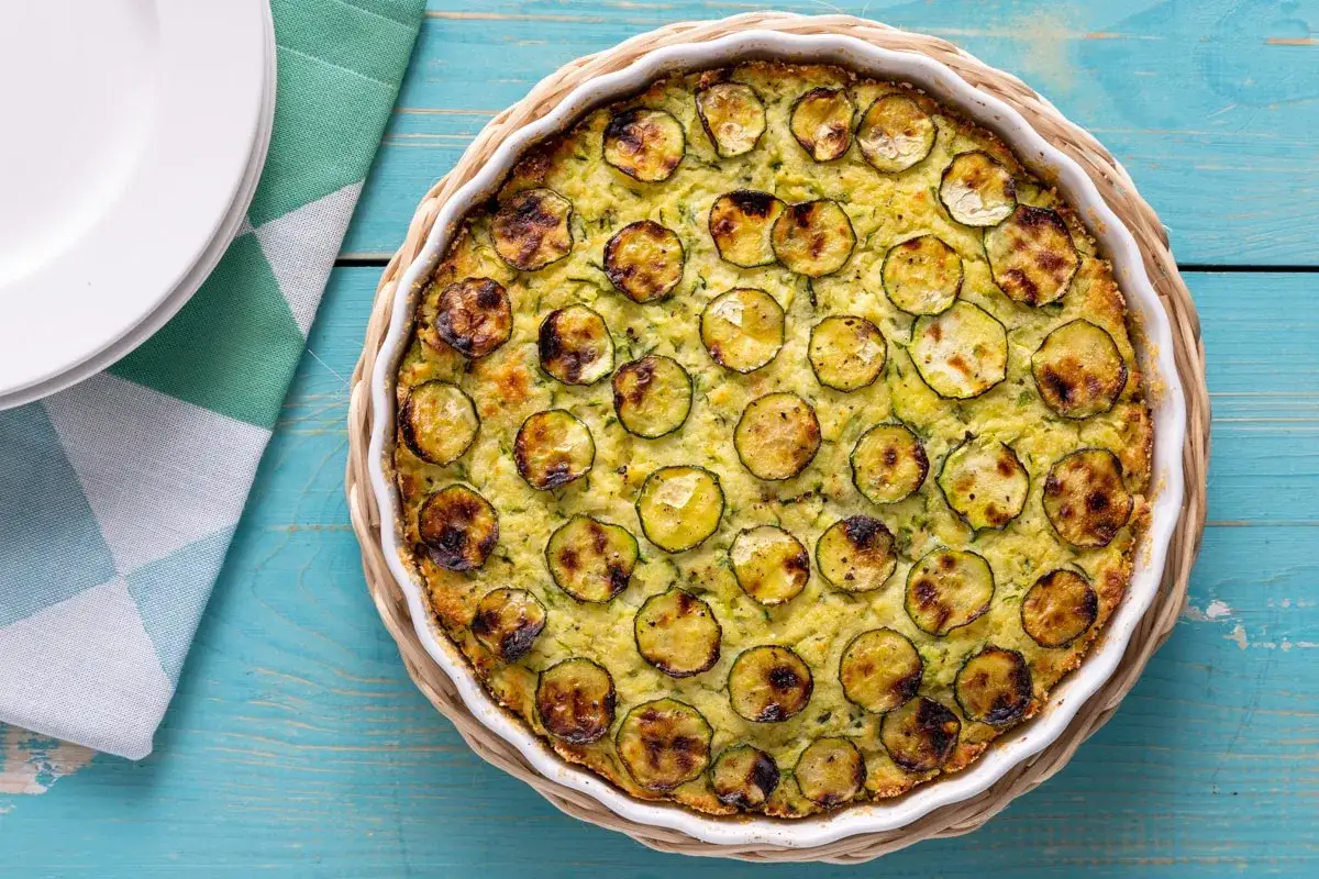 Tortino di zucchine dorato e invitante, con fette di zucchine grigliate in superficie, pronto per essere gustato.