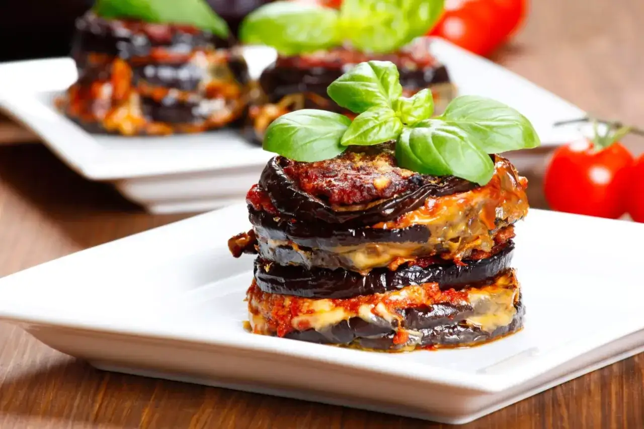Deliziosa parmigiana di melanzane a strati, guarnita con basilico fresco.
