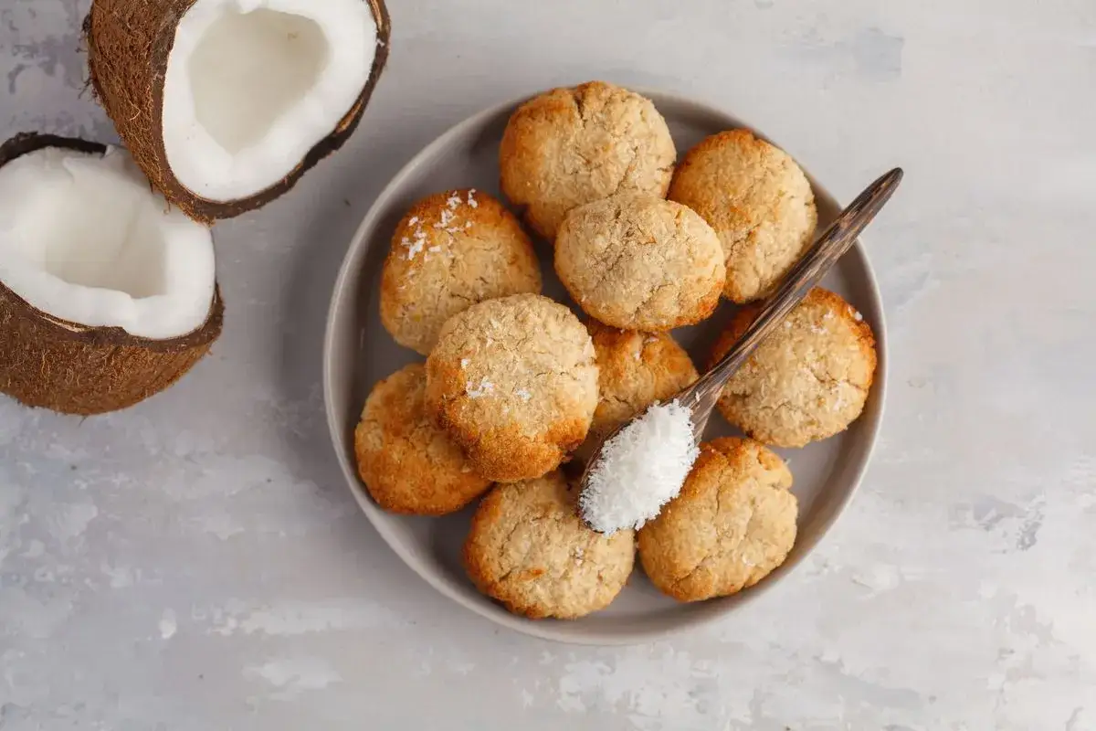 Deliziosi dolcetti al cocco su un piatto grigio, con cocco fresco e una spolverata di cocco grattugiato su un cucchiaio.
