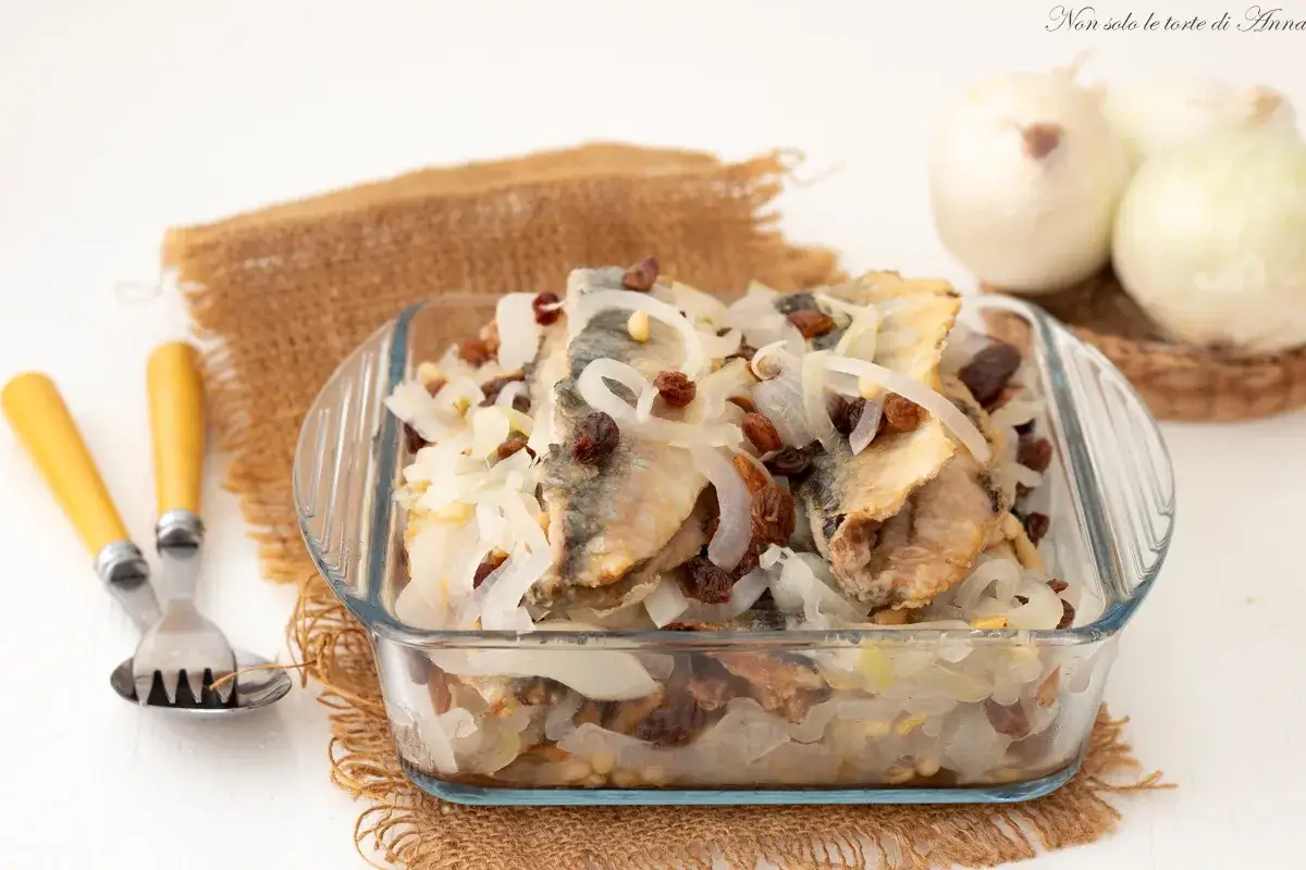 Sarde in saor in una pirofila di vetro, con cipolle, uvetta e pinoli. Un piatto tradizionale veneto pronto per essere gustato.