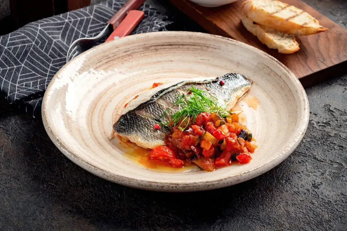 Delizioso branzino in friggitrice ad aria, servito con ratatouille e pane tostato.