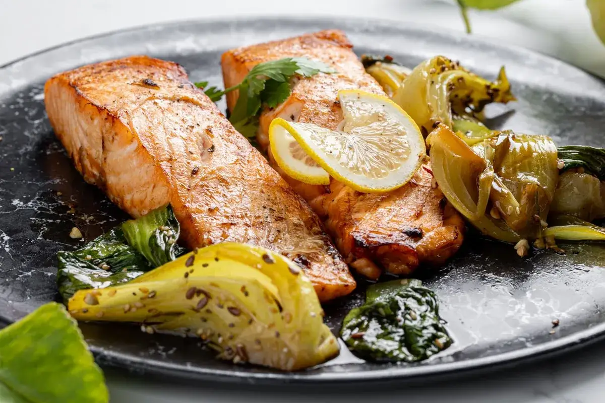 Succulento salmone in friggitrice ad aria, servito con verdure croccanti e spicchi di limone. Un piatto sano e gustoso.