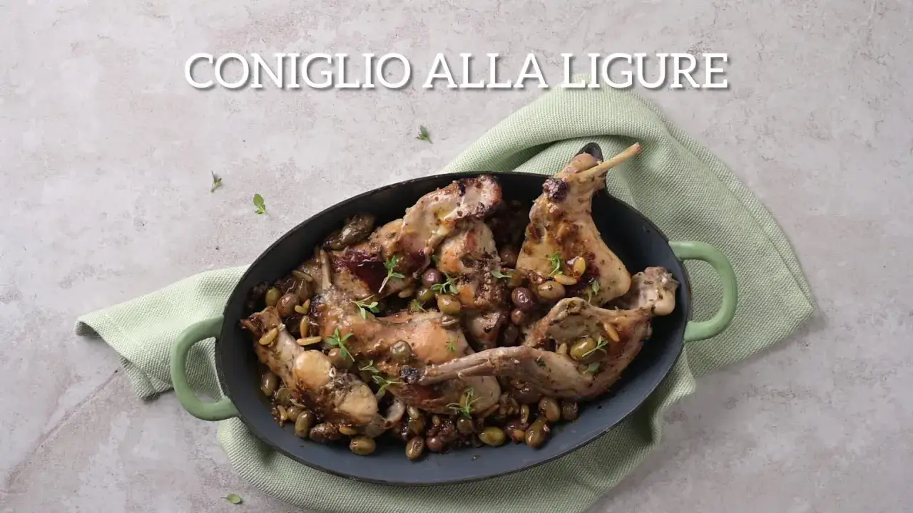 Un saporito coniglio alla ligure, cotto con olive e pinoli, servito in una casseruola verde.