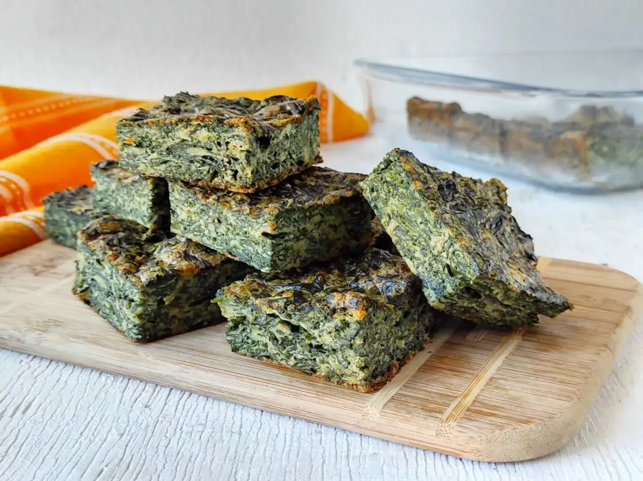 Fette di frittata di spinaci impilate su un tagliere di legno. Un piatto sano e gustoso, perfetto per un pasto veloce.
