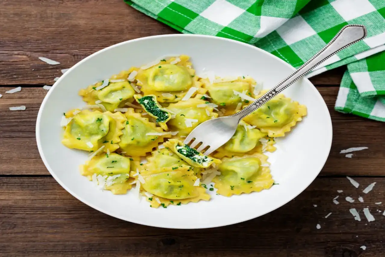 Piatto di ravioli ricotta e spinaci, conditi con parmigiano e prezzemolo, pronti per essere gustati.