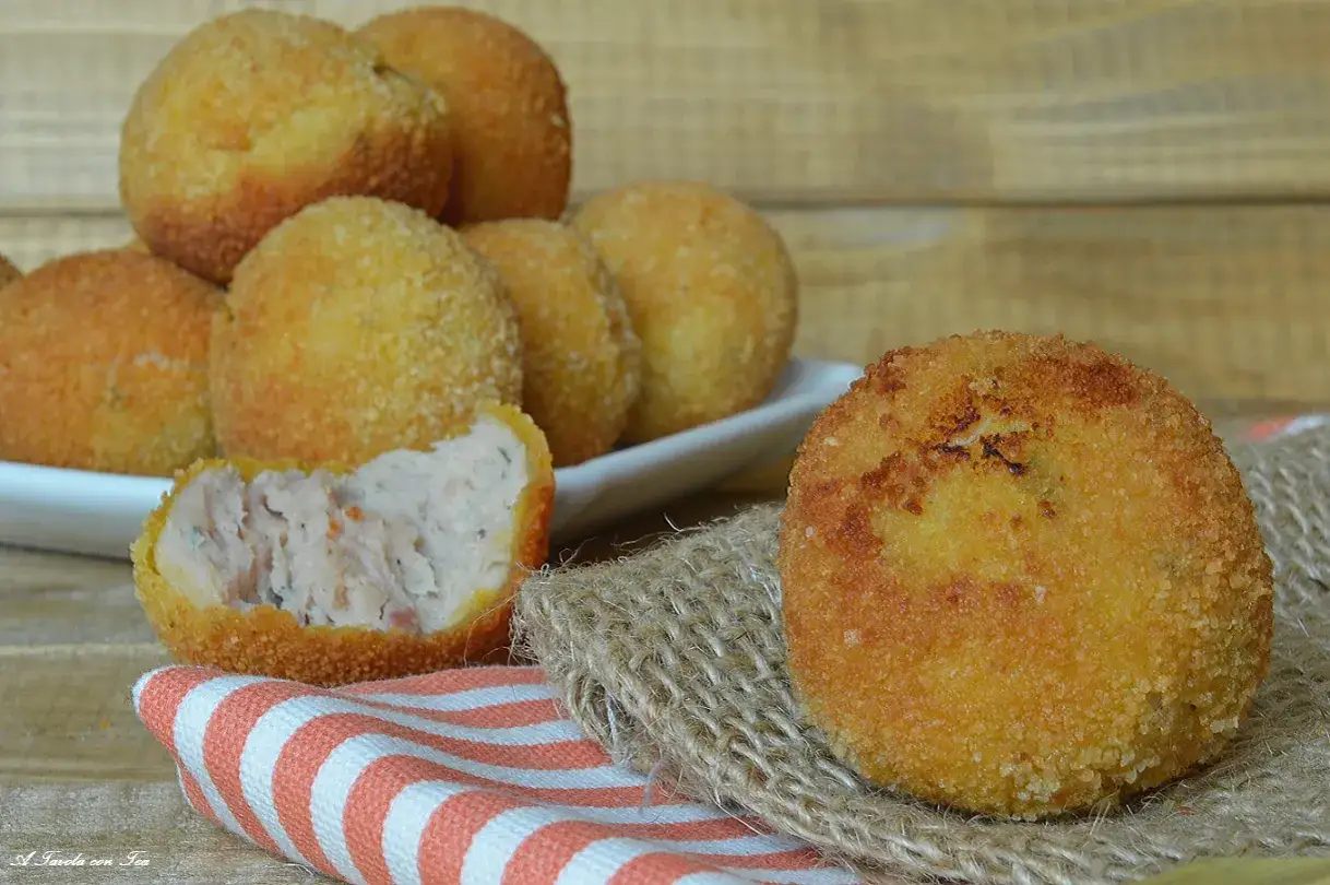Polpette di pollo dorate e croccanti, una &egrave; tagliata a met&agrave; mostrando il ripieno morbido.