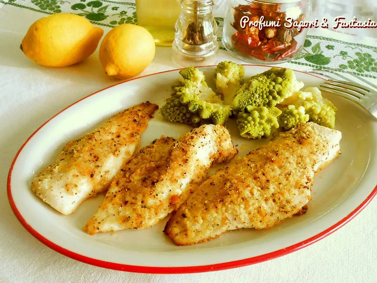 Tre filetti di merluzzo impanato al forno, dorati e croccanti, serviti con broccoli romaneschi e limoni.