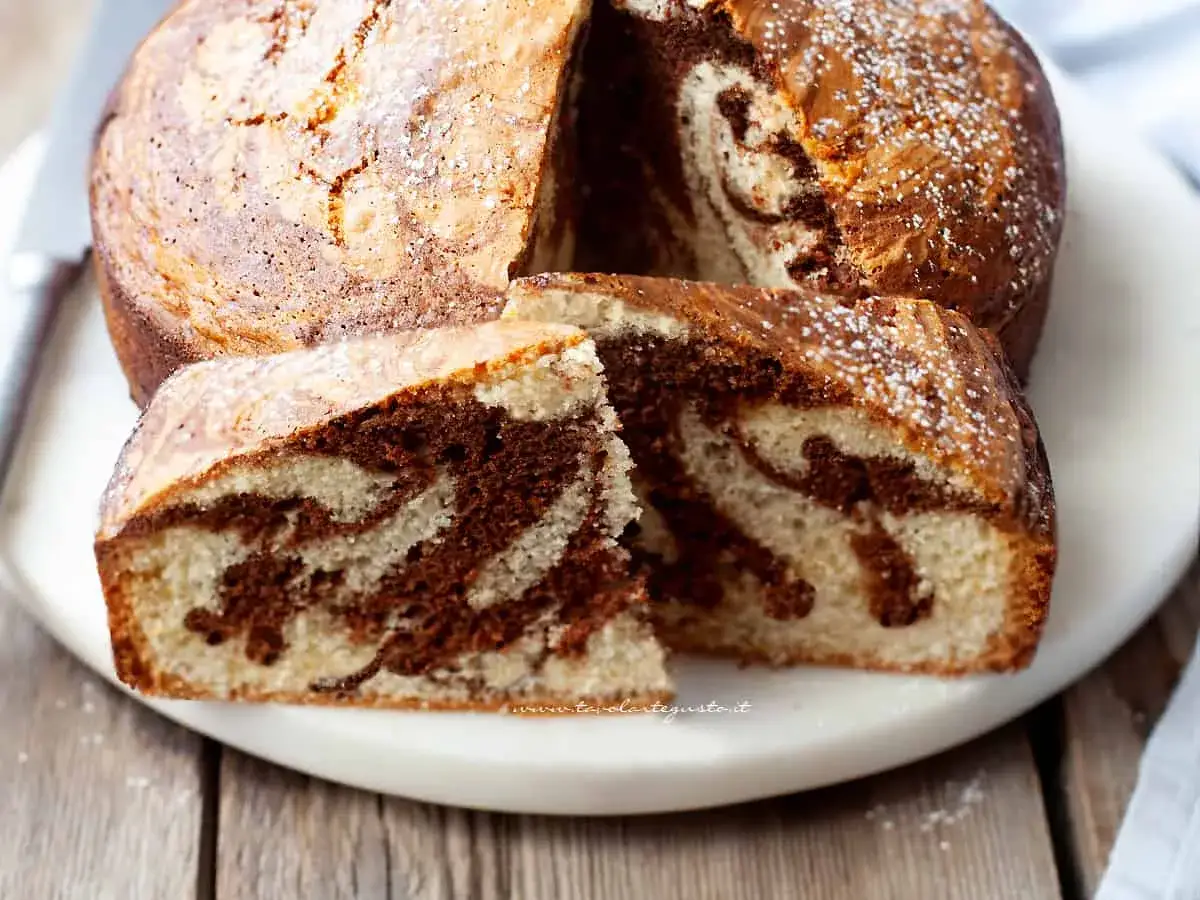 Un invitante ciambellone soffice bicolore, con un vortice di cioccolato e vaniglia, spolverato di zucchero a velo.