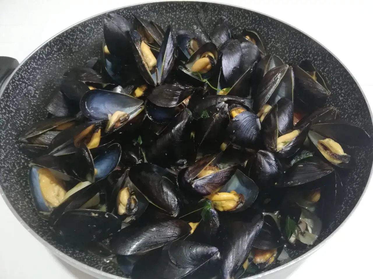 Un saporito sautè di cozze appena cucinato, con gusci aperti che rivelano la polpa succulenta.