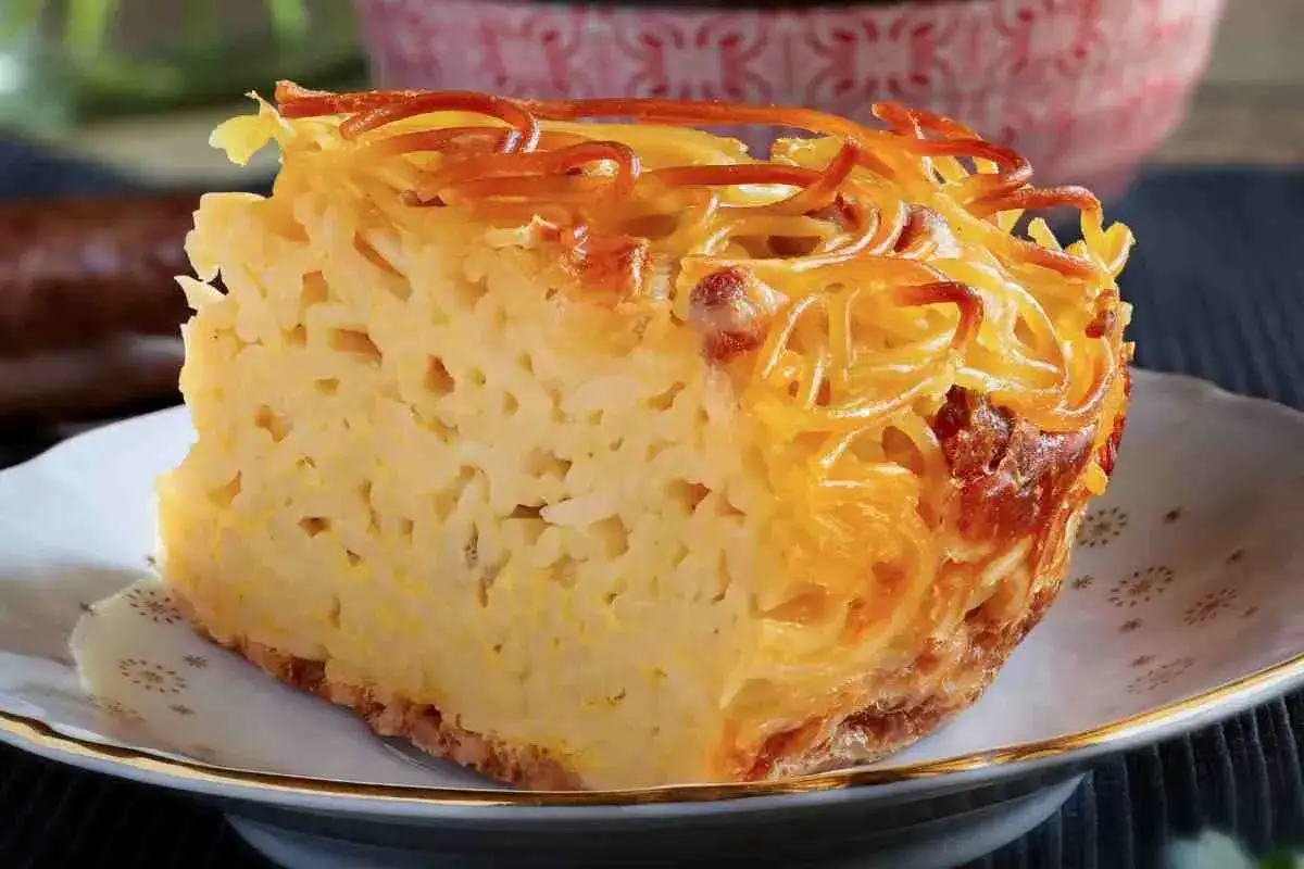 Una fetta di frittata di pasta dorata e invitante, con spaghetti croccanti in superficie e un ripieno morbido.