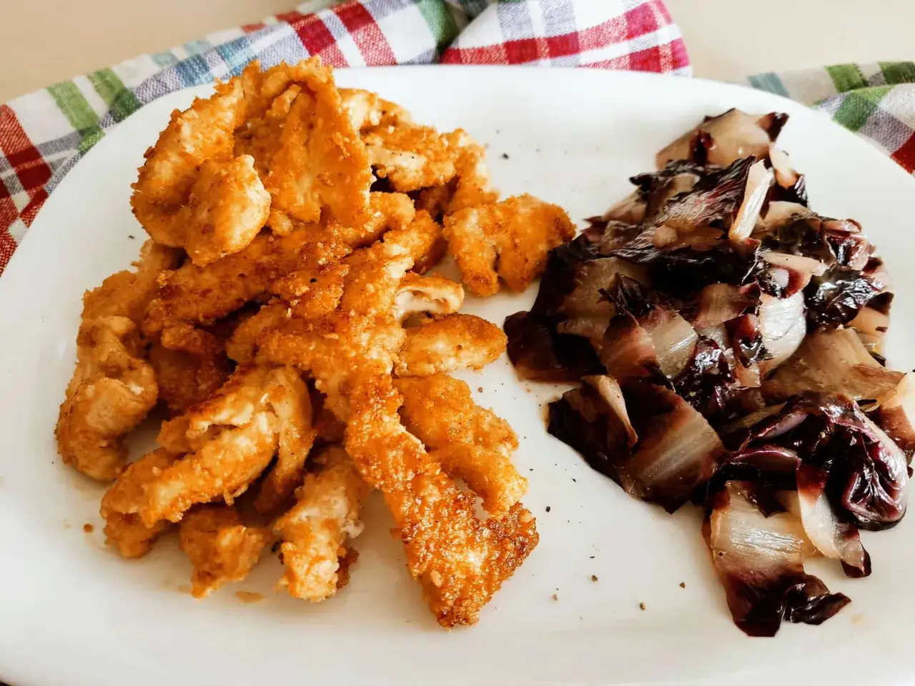 Straccetti di pollo al forno dorati e croccanti, accompagnati da radicchio stufato. Un piatto semplice e gustoso.