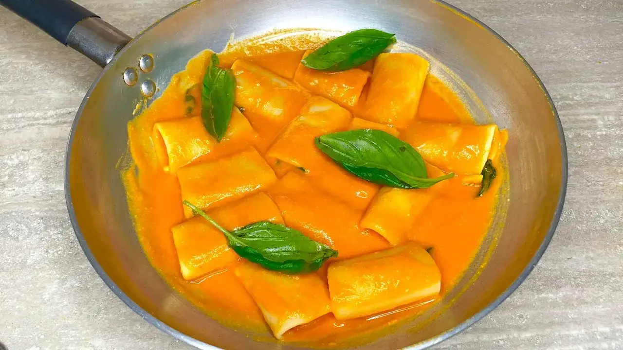 Paccheri alla Vittorio in padella, con salsa cremosa e foglie di basilico fresco. Un piatto invitante e saporito.