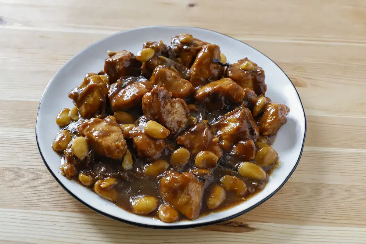 Un invitante piatto di pollo alle mandorle, con pezzi di pollo succulenti immersi in una salsa lucida e arricchiti da mandorle tostate.