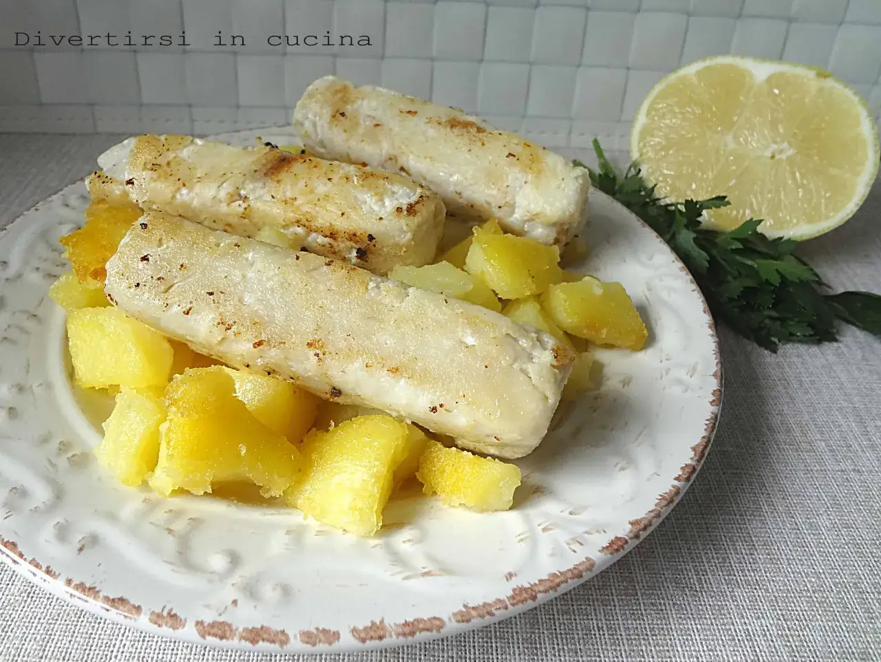 Filetti di merluzzo in padella, dorati e succulenti, serviti su un letto di patate croccanti. Un limone e prezzemolo completano questo piatto semplice e gustoso.