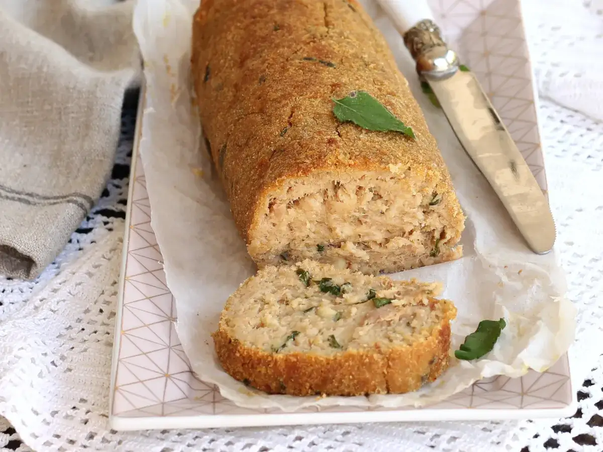Un gustoso polpettone di tonno, cotto al forno e servito su carta da forno, con una fetta tagliata.