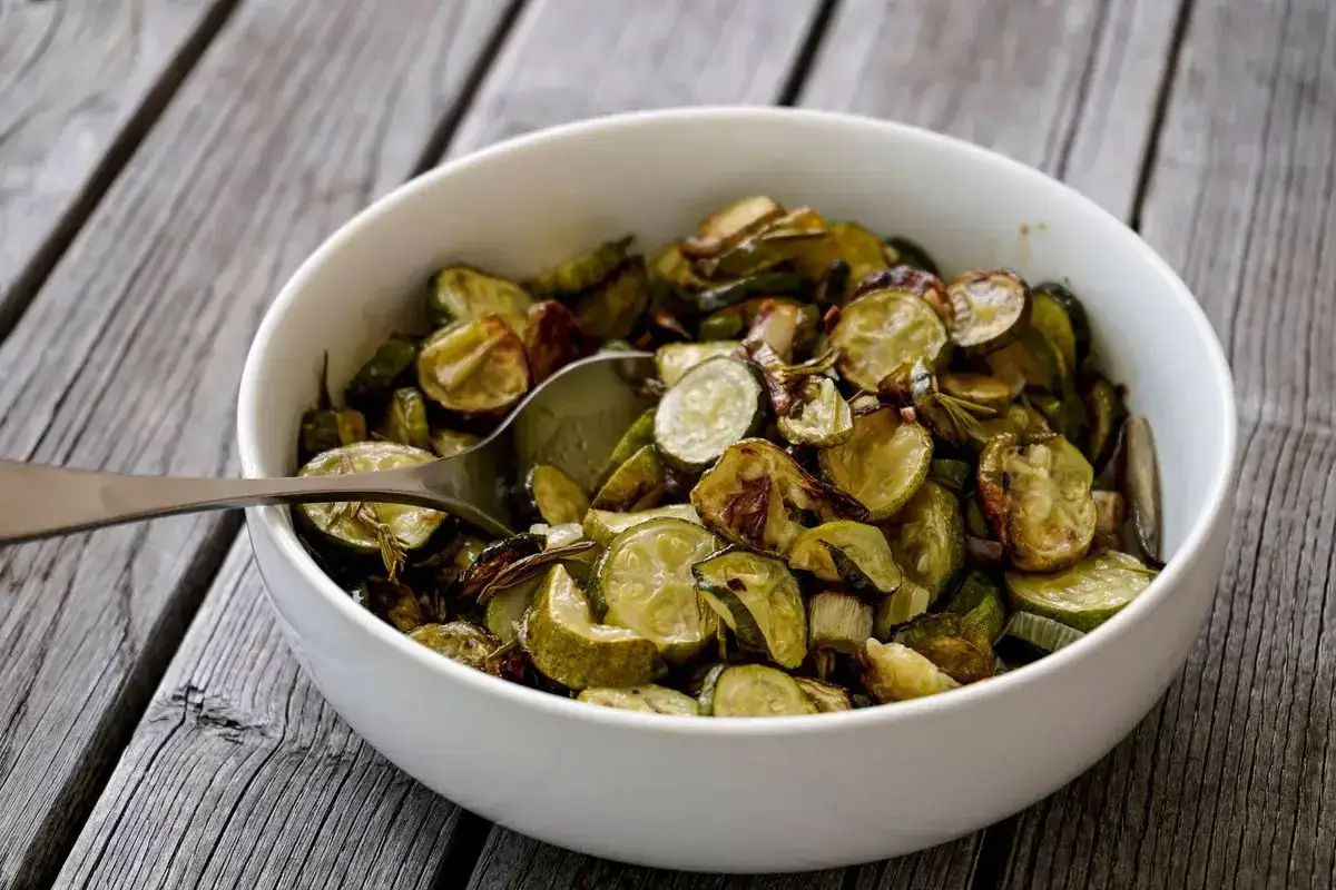 Zucchine in agrodolce, un contorno saporito e colorato, servito in una ciotola bianca su un tavolo di legno.