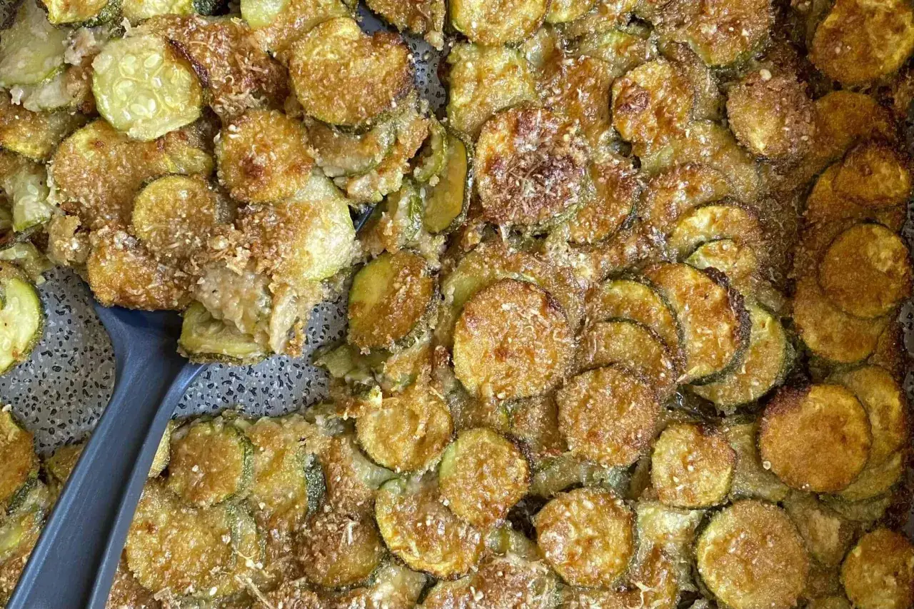 Fette di zucchine al forno, dorate e croccanti, con pangrattato e parmigiano. Un contorno saporito e invitante.