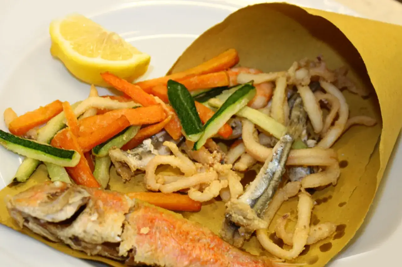 Un piatto di frittura di paranza con verdure miste e limone.