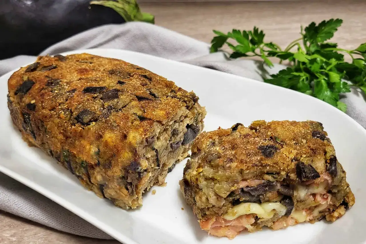 Polpettone di melanzane dorato e croccante, con un ripieno filante di formaggio e prosciutto. Un piatto gustoso e invitante.