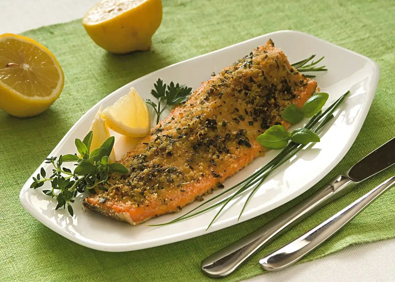Deliziosa trota salmonata al forno, croccante e profumata, servita con limone fresco e erbe aromatiche.