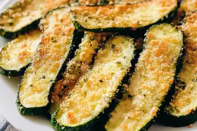 Fette di zucchine al forno, dorate e croccanti, con pangrattato e parmigiano. Un contorno saporito e leggero.